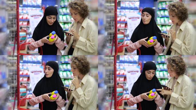 两个女孩在一个联合家庭购物阅读和比较化妆品的成分。一位戴着头巾的妇女和她的白人女友拿着事先准备好的购