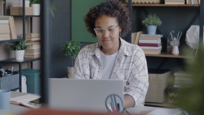开朗的非裔美国女孩在家用笔记本电脑打字学习