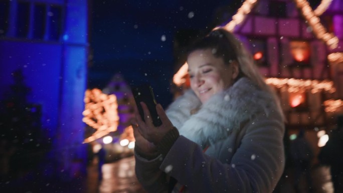 在科尔马的圣诞市场上，一名妇女正在使用她的手机