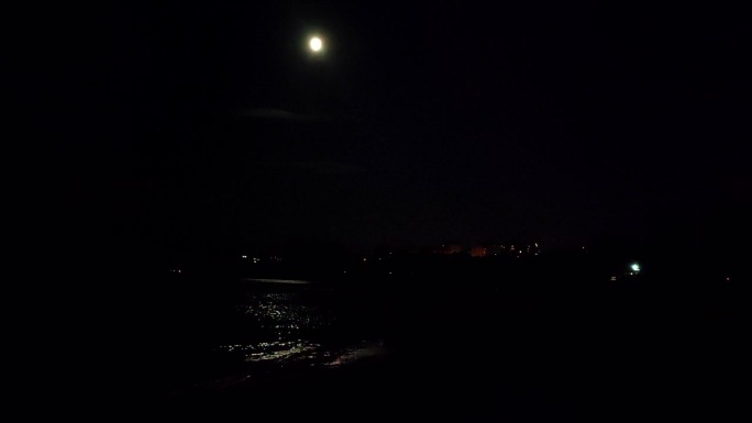 月亮在天空和月光路径上的海浪在海岸海岸的海滩上的夜晚。水面上的月球路径。月光照在海面上的海浪。自然背