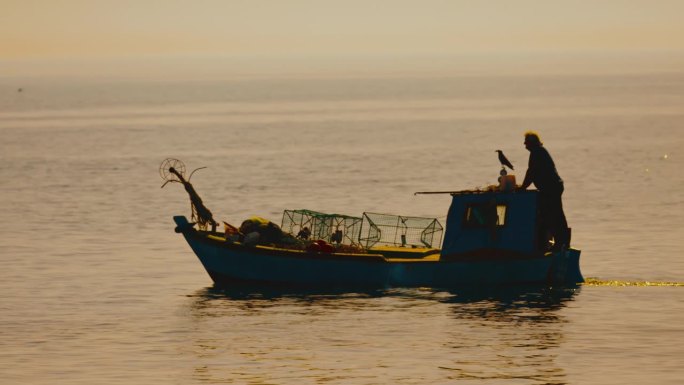日落时分，在拖网渔船上航行的人。在克罗地亚伊斯特拉，一名渔民在一艘帆船上划船