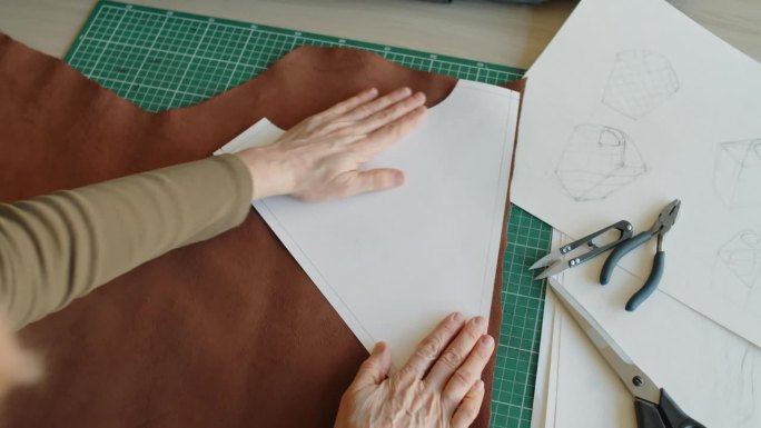 一个无法辨认的女人的手在一块皮革上放置图案