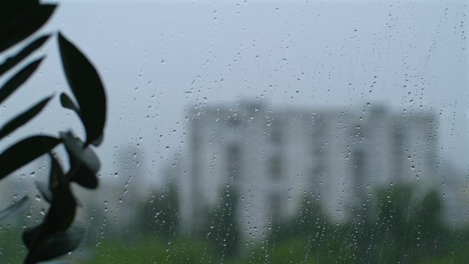 雨滴落在窗户表面。水滴落在玻璃上。从家里的窗户看下雨的暴风雨天气