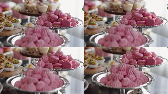 一张漂亮而甜蜜的桌子;马卡龙，小零食，三明治，粉色汉堡，糖果，饼干，纸杯蛋糕。一个装饰的新娘准备室桌