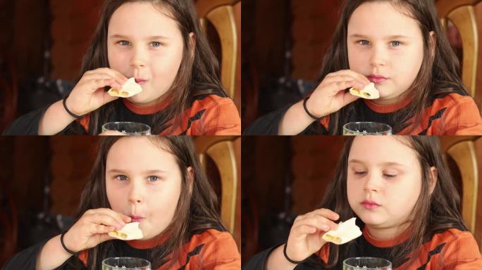 专注，热情，肥胖的黑发小女孩嚼着沙瓦玛或三明治，喝着茶。暴饮暴食