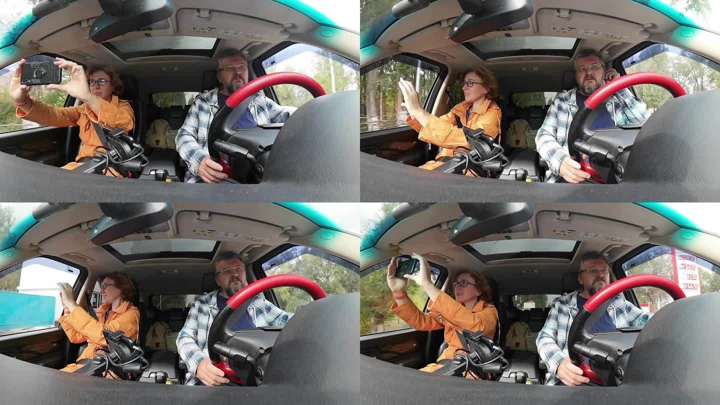 一对成熟的夫妇在秋天的小镇街道上开车。女人正隔着窗户用手机拍视频。汽车内景