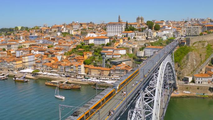 在葡萄牙波尔图的杜罗河上，地铁列车行驶在多姆·路易斯一世桥上，人行道上有行人。广角镜头
