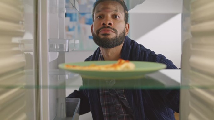 一个人打开冰箱，看着空空的架子上的一块披萨