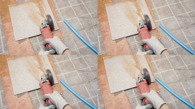 近距离使用圆锯机刀片切割瓷砖地板的人的手，并使用水来防止切割引起的灰尘分散。