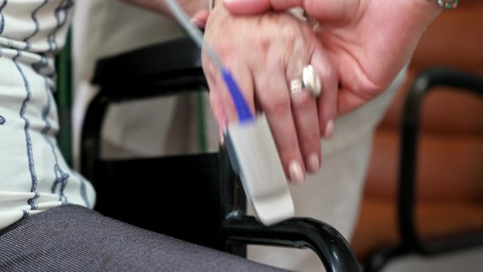 一位老年妇女的饱和度测量。戴着医用手套的医生正在给一位老妇人的手指测量脉搏血氧仪。关心老年人健康。高