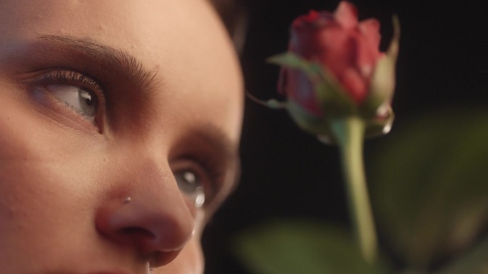 性感的女人用红色的口红和纹身黑色背景工作室拍摄跳舞与一个单一的红玫瑰，并看着花