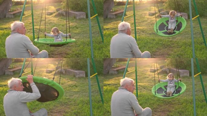 祖父在夏日夕阳下荡秋千。爷爷和孙子坐在公园里的秋千上。60多岁的老爷爷推着漂亮的宝宝玩跷跷板。老人和