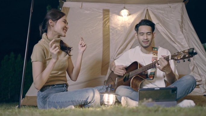 亚洲年轻夫妇在度假露营时弹吉他