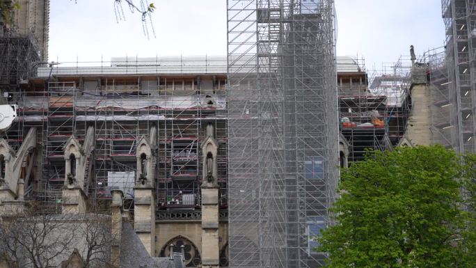 在重建和翻新期间，巴黎圣母院在脚手架下的火灾损毁立面特写侧视图。
