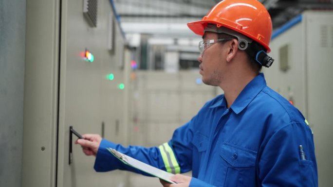 电气工程师的专业知识细致地检查并记录在工厂配电室的剪贴板上的重要信息。工程师在确保工业电气系统的平稳