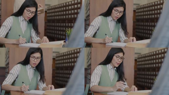 聪明的亚洲女孩在图书馆学习，准备大学考试，写作和阅读书籍