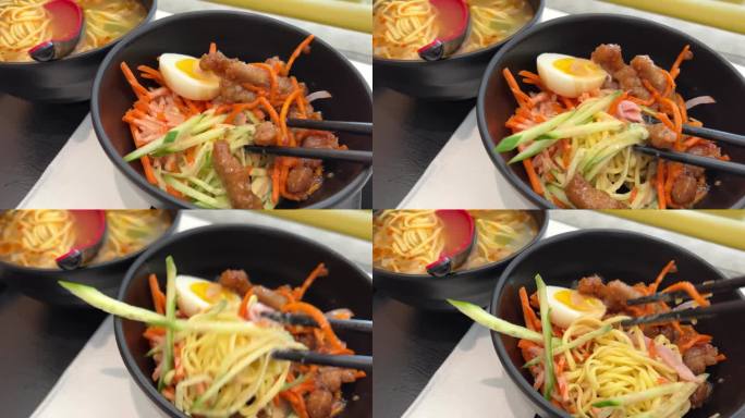 台湾风味冷干面半水煮蛋料理亚洲菜用黑盘子用筷子煮粉条从蔬菜黄瓜胡萝卜切成丝的健康食品