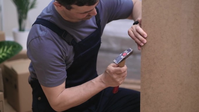 定制家具生产的重点是工人将钉子打入木制衣柜