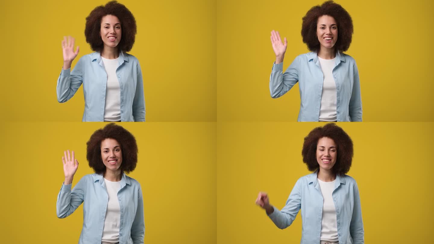 年轻的微笑的非裔美国妇女握手说再见站在橙色的工作室背景