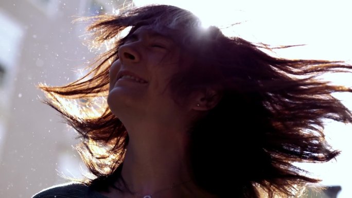 阳光下30岁的女人用火炬摇头发的慢动作