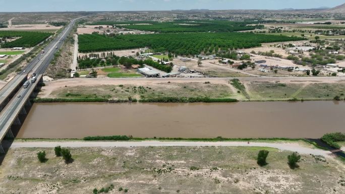 里奥格兰德在拉斯克鲁塞斯，新墨西哥州附近的山核桃果园。航拍卡车跟随美国西南部棕色泥泞的河流。