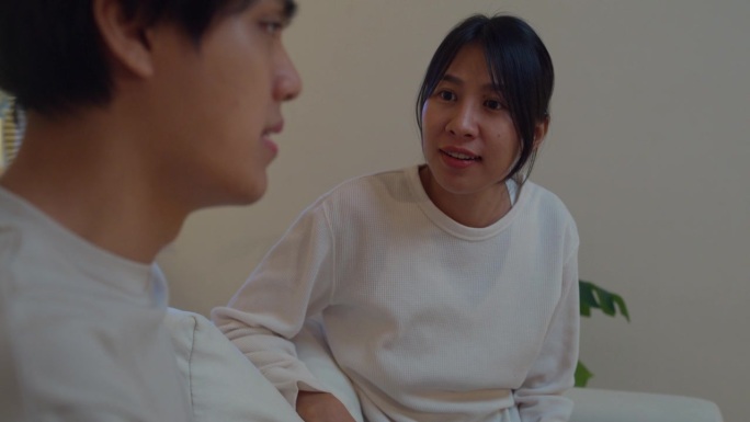 晚上，年轻的亚洲夫妇坐在家里客厅的沙发上争吵和打架。生活方式花时间在家里。