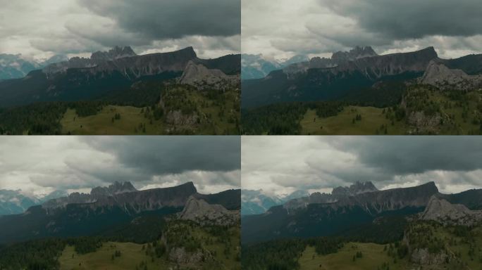 鸟瞰图，远处陡峭高大的山脉为背景，山间有山谷的绿色森林，暴风雨前，雨天，电影级