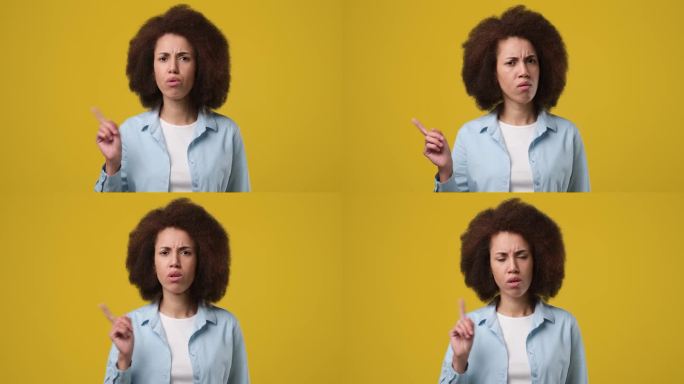 年轻的非裔美国女性站在橘黄色的摄影棚背景上，用食指说不