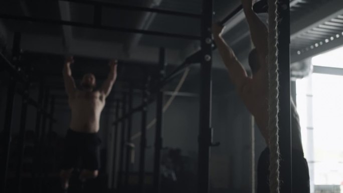 运动员在健身房训练，英俊的肌肉男裸体上身在横梁上做引体向上