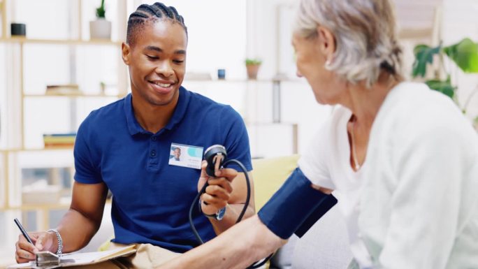 照顾者，黑人男子写作或在医院咨询血压的老年妇女监测心脏。保健、高血压咨询或医务男护士陪同病人进行检查