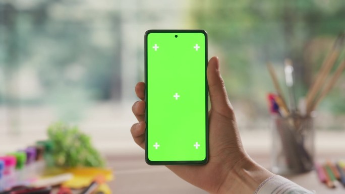 设计师手持绿色屏幕模拟显示屏的智能手机的视角视图。一个人拿着一个设备的第一人称视角，与应用程序，软件