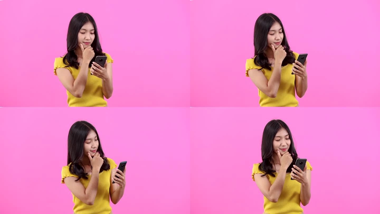 画像上快乐的亚洲妇女用智能手机购物或在粉红色背景下搜索互联网，年轻女孩在不经意间拿着手机，人们用数字