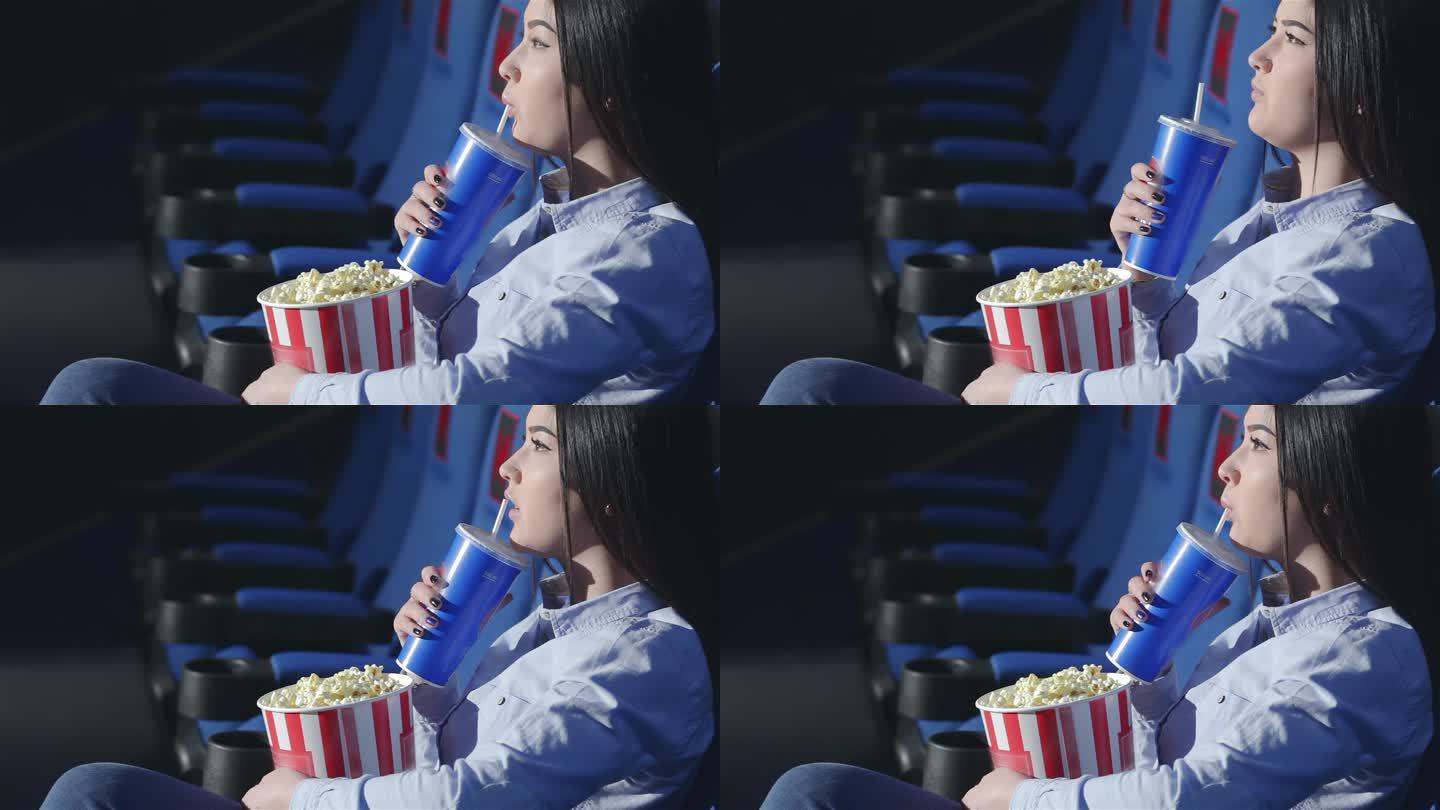 侧影中的亚洲女孩在电影院喝苏打水