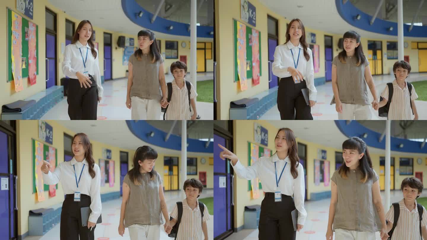 图为，学龄前儿童与老师、妈妈一起走过学校走廊。老师指着他旁边的现代化教室。