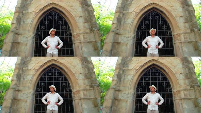 一个戴着白色草帽的男人站在一座古老的哥特式建筑前，若有所思地转过头来。追求。地下室