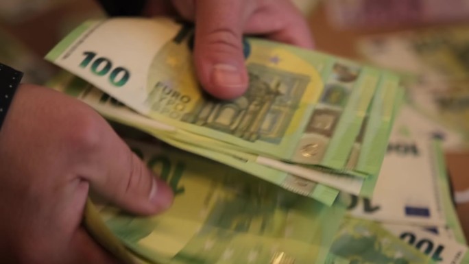 男性的手迅速数出现金100欧元，并拿出一部分钱来分配收入