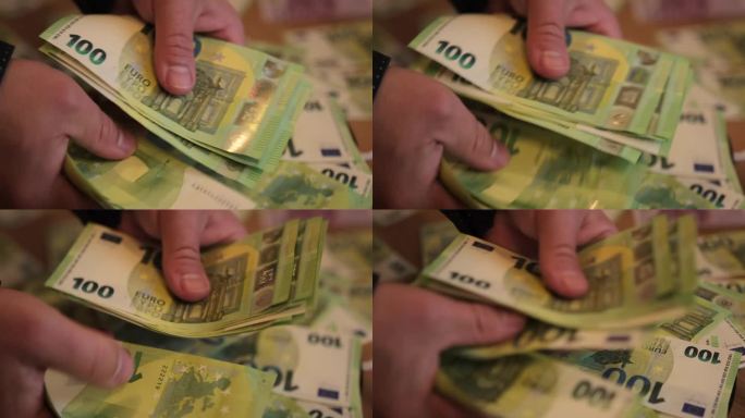 男性的手迅速数出现金100欧元，并拿出一部分钱来分配收入