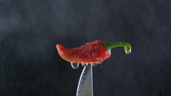 慢镜头:红辣椒刀尖在水喷雾。自然的烹饪