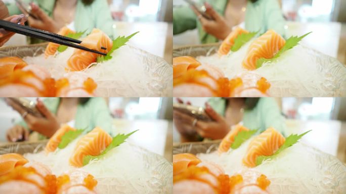 亚洲妇女用筷子夹生鲑鱼，寿司很好吃。