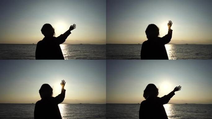 美女站在海边向太阳挥手女人招手开心挥手