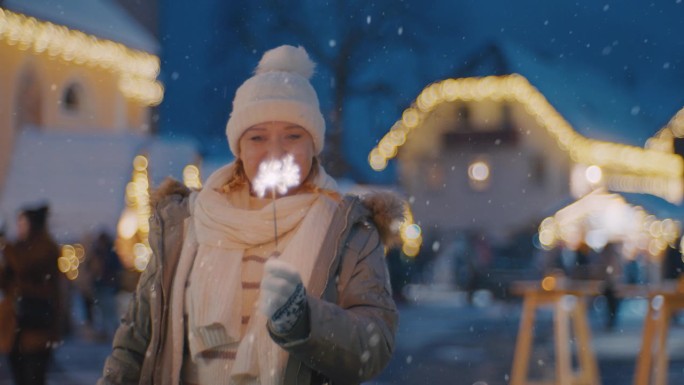 一名妇女在雪地里欣赏圣诞市场上耀眼的焰火