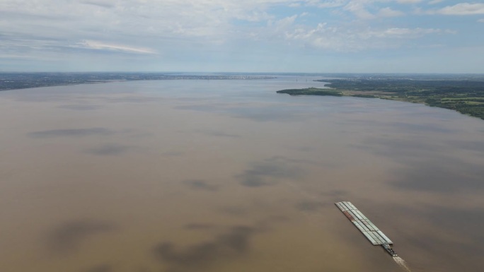 航拍的一艘运输船航行在连接阿根廷和巴拉圭的广阔的帕拉纳<e:1>河上，展示了河流运输对贸易和商业的重