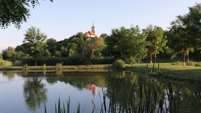 在活动花园的池塘上荡起涟漪，反射出教堂尖塔和岸边的树木