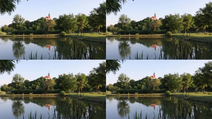 在活动花园的池塘上荡起涟漪，反射出教堂尖塔和岸边的树木