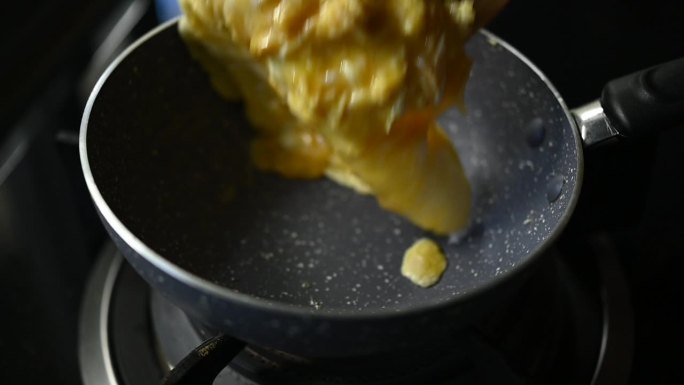 炒鸡蛋，煎蛋卷，用黑锅煮早餐，慢动作煎蛋的场景