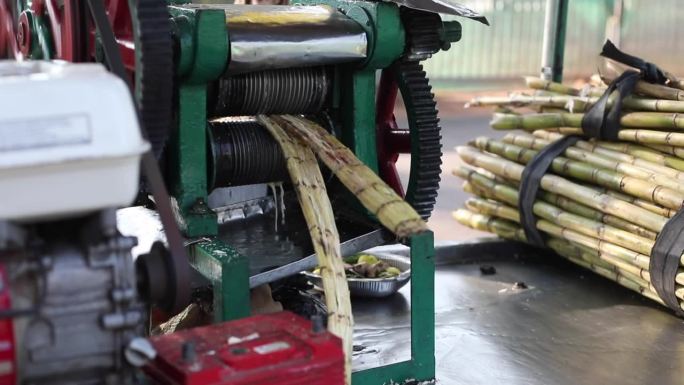 男工人用旋转行走元件用工艺机器进行甘蔗榨汁加工，经营