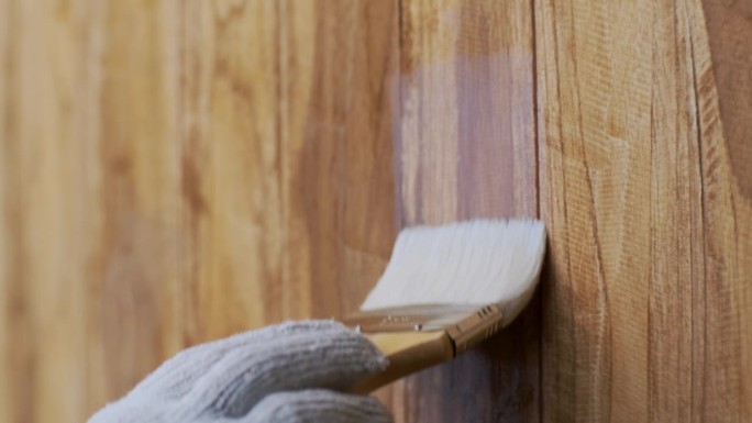 手放在手套里，用刷子在木墙上涂漆或保护性清漆。保护木材不受潮。