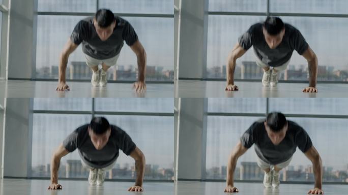 肌肉男健美运动员在玻璃墙健身房做俯卧撑训练，专注于锻炼