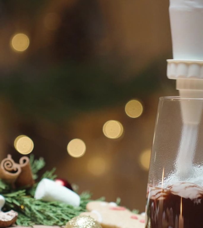 垂直视频。家里的圣诞装饰，桌上的糖果，一个女人从糕点袋里挤出鲜奶油到可可里。