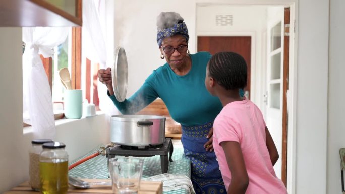 奶奶和孙女一起打开热气腾腾的锅盖